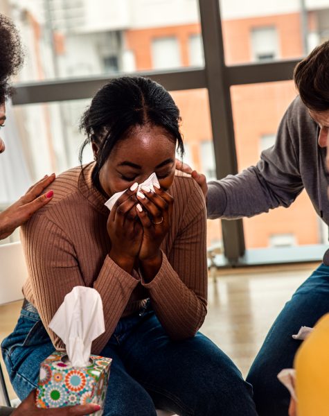 Diverse group of people sitting in circle in group therapy session.